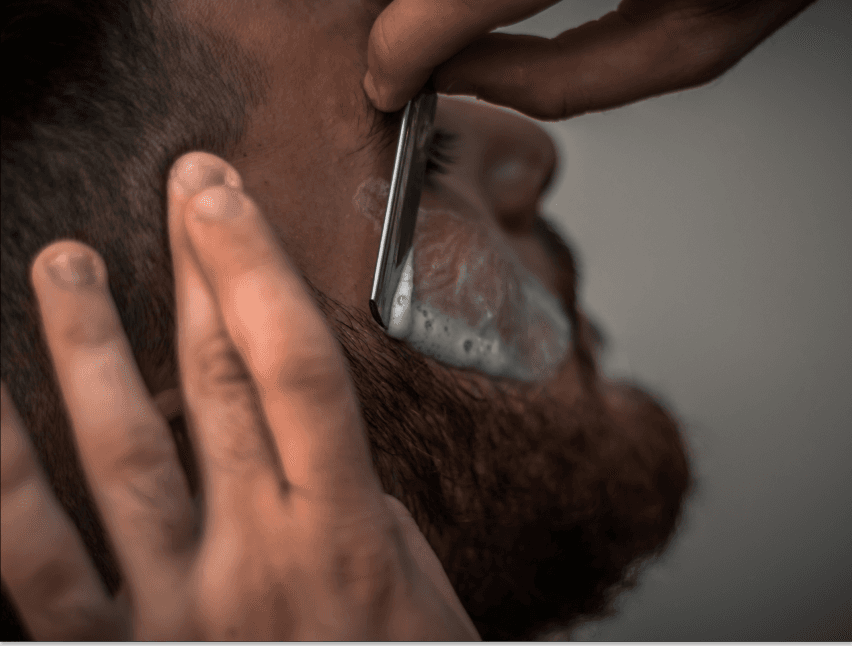Coiffeur realisant une taille de barbe en gros plan